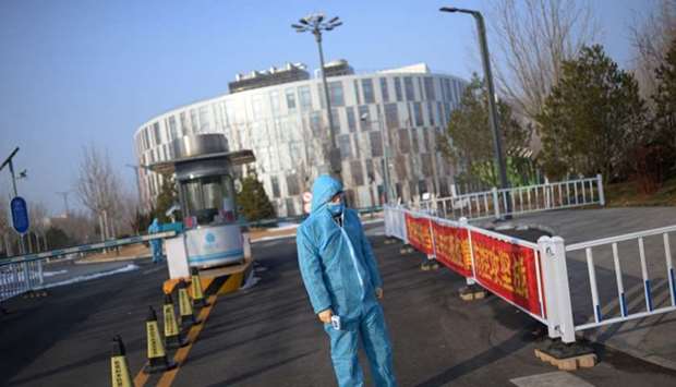 A security guard wearing a protective suit and a face mask stands as he holds a thermometer in front of the entrance to the China Transinfo Technology Co,in the morning after the extended Lunar New Year holiday caused by the novel coronavirus outbreak, in Zhongguancun Software Park, in Beijing.