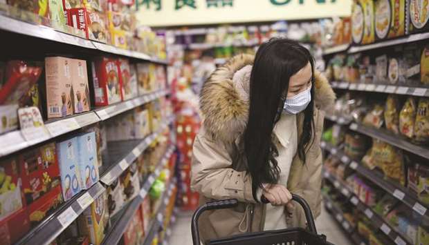A woman wearing a surgical face mask looks for products at a supermarket in Beijing yesterday.