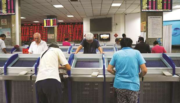 Investors look at computer screens showing stock information at a brokerage house in Shanghai.