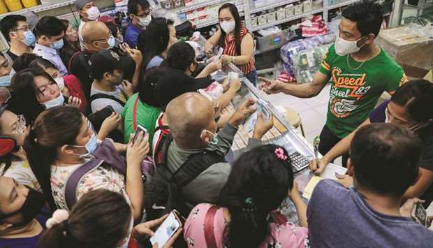 People scramble to buy face masks in a medical supply store a day after the Philippine government confirmed the first novel coronavirus case, in Manila, yesterday.