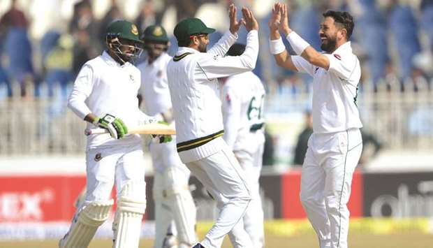 Pakistanu2019s spinner Yasir Shah (right) celebrates with captain Azhar Ali (centre) after taking last wicket of Bangladesh during the fourth day of the first at the Rawalpindi Cricket Stadium in Rawalpindi yesterday. (AFP)
