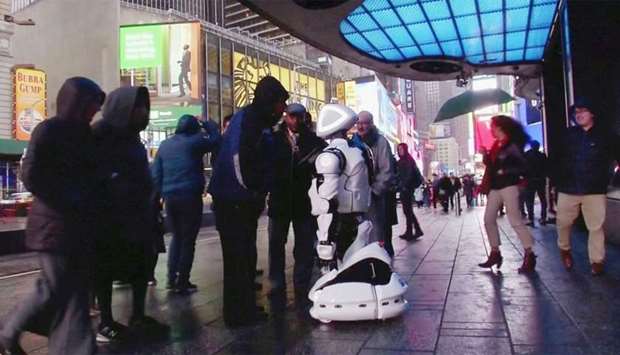 Passers-by in Times Square interact with a Promobot robot that informs the public about the symptoms of coronavirus and how to prevent it from spreading, in this still frame obtained from video, in New York City
