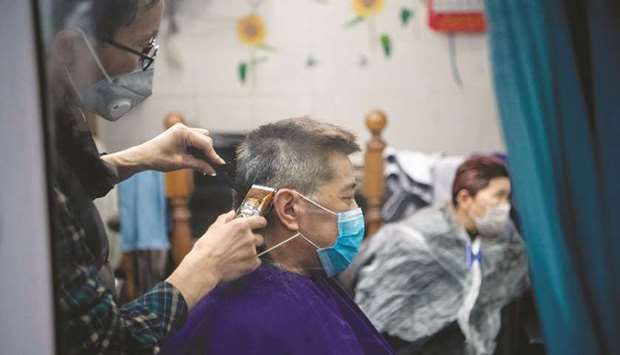 A man wearing a protective face mask has his hair cut by a barber in Shanghai yesterday.
