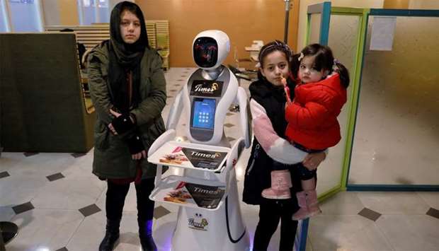 Afghan girls pose for a photo with a waitress robot (Timea) at the Times Fast Food restaurant in Kabul