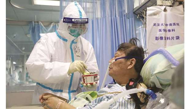 A nurse in a protective suit feeds a novel coronavirus patient inside an isolated ward at Zhongnan Hospital of Wuhan University, during the Lantern Festival, which marks the end of the Chinese Lunar New Year celebrations, in Wuhan, Hubei province, China, on Saturday.