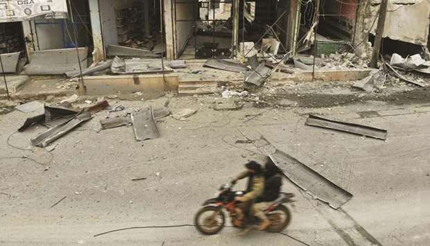 An aerial view shows Syrian men riding a motorcycle past destroyed shops in the village of Maaret al-Naasan in the Idlib province, yesterday following a weeks-long regime offensive against the countryu2019s last major rebel bastion.