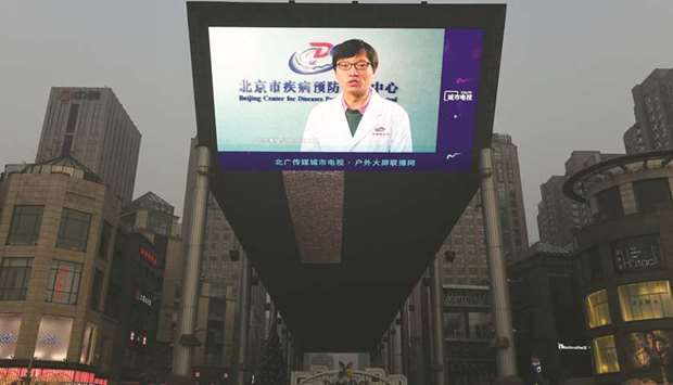 A news item about the COVID-19 coronavirus plays on a giant screen outside a shopping mall in Beijing yesterday.
