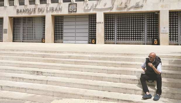 A man sits on the stairs in front of the central bank building in Beirut (file). The IMF said that Lebanon asked it for u201cadvice and technical expertise on the macroeconomic challenges facing the economy,u201d according to a statement.