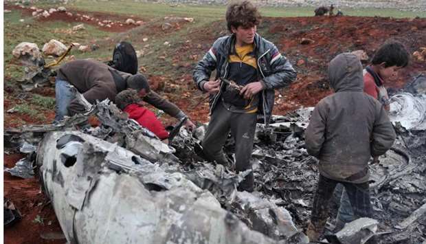 Syrians inspect the wreckage of a military helicopter belonging to government forces after it was shot down over the western countryside of Aleppo province