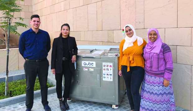 GU-Q's Sustainability Club members with the machine that converts food waste into nutrient-rich soil.