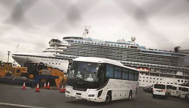 A bus with a driver wearing protective gear departs from the dockside next to the Diamond Princess cruise ship, which has around 3,600 people quarantined onboard due to fears of the new COVID-19 coronavirus, at the Daikoku Pier Cruise Terminal in Yokohama port yesterday.