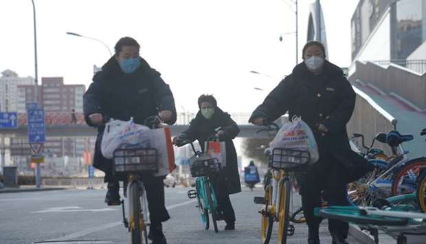Women wearing face masks ride shared bicycles in Beijing