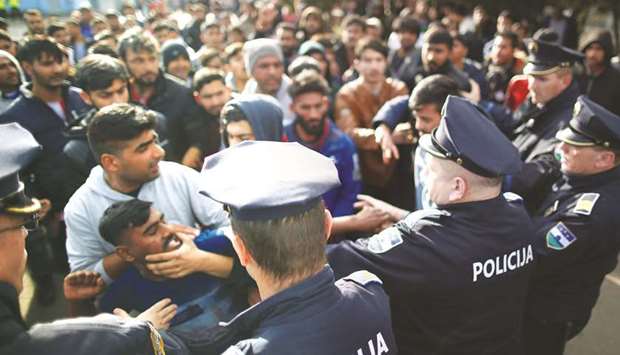 Migrants scuffle with police as they try to block a road in front of the Miral refugee camp in Velika Kladusa.