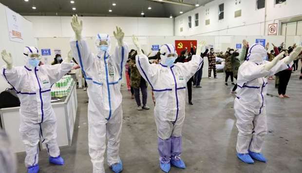 Medical workers in protective suits dance with patients inside the Wuhan Parlor Convention Center that has been converted into a makeshift hospital following an outbreak of the novel coronavirus, in Wuhan, Hubei province, China