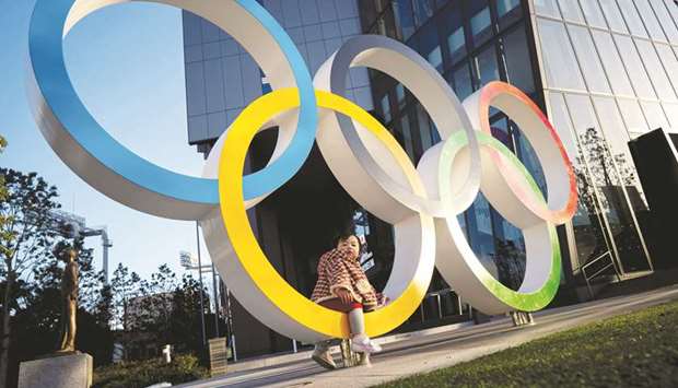 A child poses for photographs with the Olympic rings in front of the Japan Olympic Museum in Tokyo, Japan, yesterday. (Reuters)