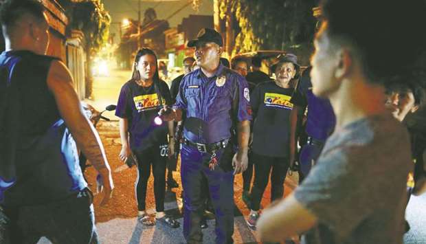 A policeman reprimands men for drinking in public, while accompanying a volunteer group of women patrollers on the streets of Pateros, Metro Manila.