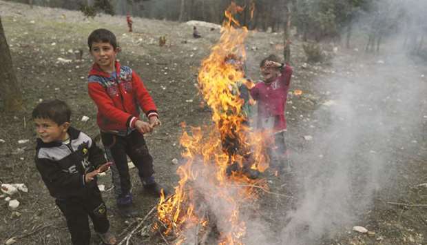 Internally displaced children warm themselves around a fire in Qatmah village, West of Azaz, yesterday.