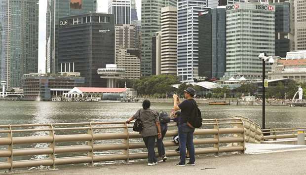 A man takes a photo as the financial business district looms in the background in Singapore. The city-state downgraded its 2020 growth estimate to a range of -0.5% to 1.5% yesterday.