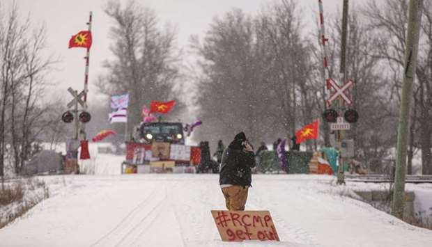 A man with a sign stands near the site of a rail stoppage on Tyendinaga Mohawk Territory, as part of a protest against British Columbiau2019s Coastal GasLink pipeline, in Tyendinaga, Ontario.