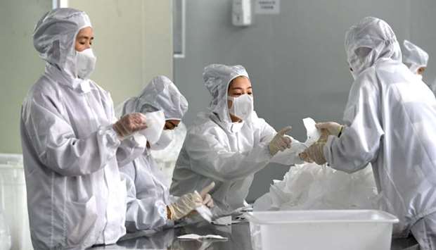 Employees work on a production line manufacturing face masks at a factory, as the country is hit by an outbreak of the novel coronavirus, in Fuzhou, Fujian province, China