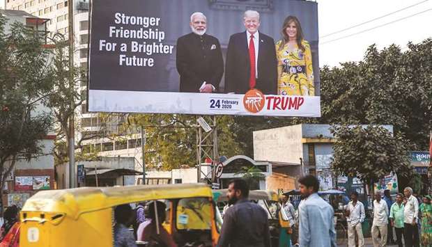 Commuters and pedestrians pass below a billboard depicting US President Donald Trump, his wife Melania Trump and Prime Minister Narendra Modi in Ahmedabad yesterday.