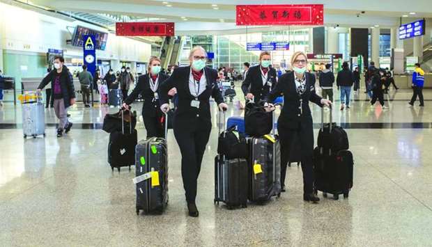 Flight attendants wear protective masks as they walk through the arrivals hall at the Hong Kong International Airport