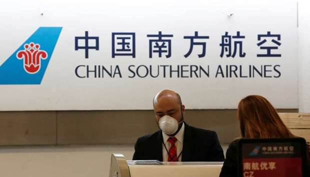 A China Southern Airlines employee wears a surgical mask as a preventive measure in light of the coronavirus outbreak in China, while he attends a customer behind the counter at Benito Juarez international airport in Mexico City