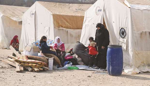 Displaced Syrians sit outside their tents at Deir al-Ballut camp in Afrinu2019s countryside, along near the border with Turkey, yesterday.