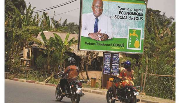 Riders drive past a campaign billboard of presidential candidate of the Alliance of Democrats for Integral Development, Loved Tchaboru00e9 Gogue, in Kpalime, Togo.