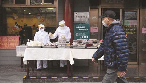 Restaurant workers wear protective clothing as they prepare food to sell on the street in Beijing.