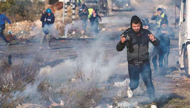 Palestinian demonstrators and journalists rush for cover from tear gas canister fired by security forces during clashes following a rally protesting a US peace plan proposal, at the northern entrance of the West Bank city of Ramallah, yesterday.
