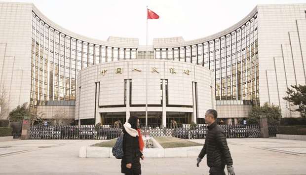 Pedestrians walk past the Peopleu2019s Bank of China headquarters in Beijing. The one-year loan prime rate is lowered to 4.05% from 4.15%, the PBoC said yesterday.