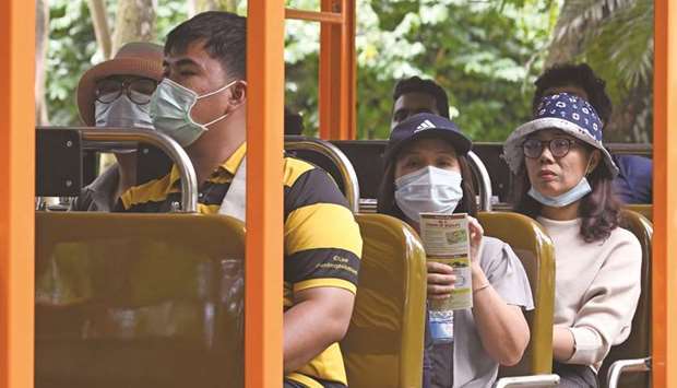 Visitors, wearing protective facemasks amid fears over the spread of the COVID-19 novel coronavirus, take a tour in a tram around the Singapore Zoo on February 18.