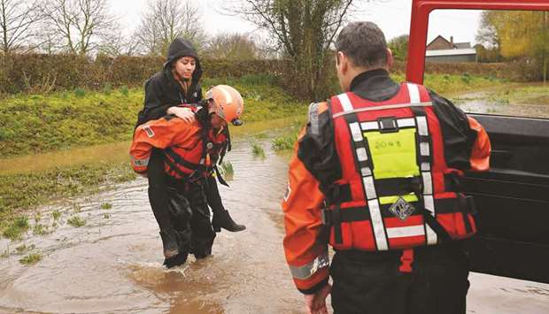 Hereford Fire and Rescue personnel help carry a woman in a flooded street in the village of Hampton Bishop in Herefordshire yesterday.