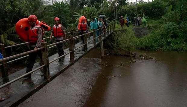 Rescue workers walk past a bridge as they search for students who were missing after a tidal surge swept them away during a school trip, in Sleman, Yogyakarta, Indonesia
