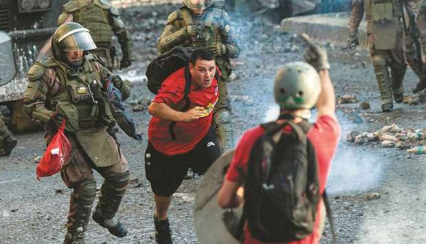 A demonstrator is chased by police during clashes in Santiago on Friday.