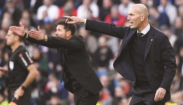 Atletico Madridu2019s coach Diego Simeone (left) and his Real Madrid counterpart Zinedine Zidane gesture during the La Liga match at the Santiago Bernabeu stadium. (AFP)