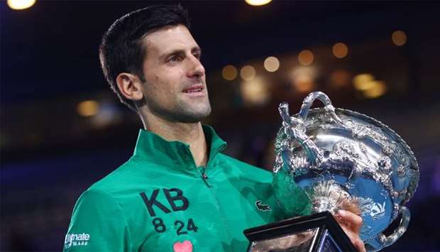 Serbia's Novak Djokovic celebrates with the trophy as he wears a jacket in tribute to Kobe Bryant, after winning his match against Austria's Dominic Thiem.