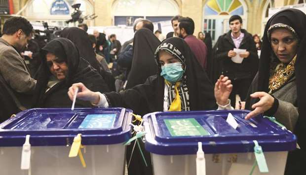 A woman wears a face mask as she casts her vote during parliamentary elections at a polling station in Tehran, yesterday.