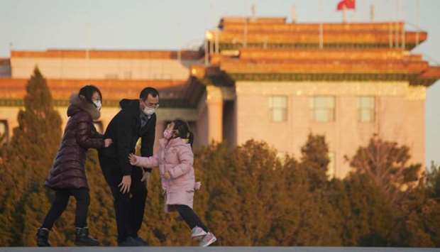 Parents wearing face masks play with their daughter with the Great Hall of the People seen in the background, following an outbreak of the novel coronavirus in the country, in Beijing