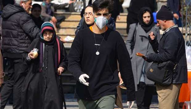 A young Iranian man wearing a protective mask, walks in a busy street in the capital Tehran