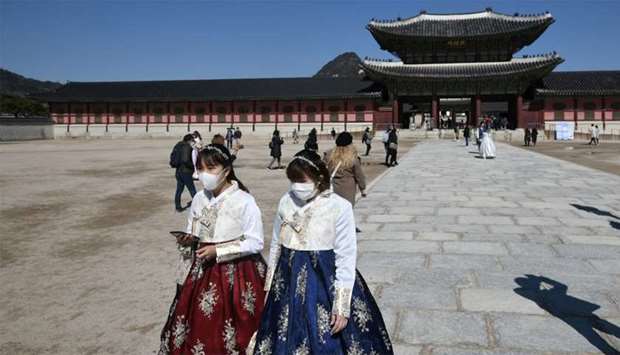 People in traditional Korean hanbok dresses wear face masks as they visit Gyeongbokgung palace in Seoul