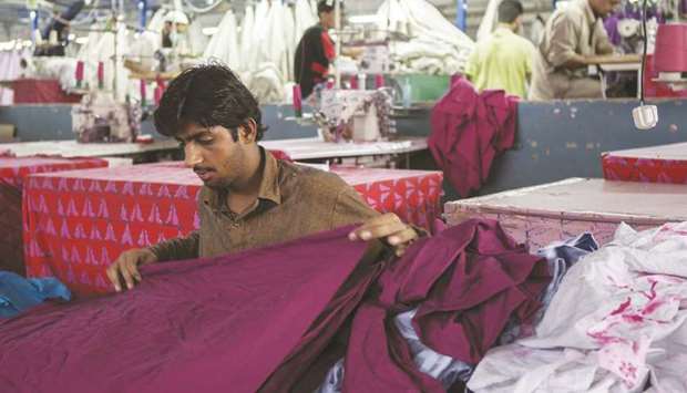 A worker inspects a piece of fabric ahead of stitching at a textile manufacturer in Karachi. Pakistanu2019s textile industry is struggling to implement the all-inclusive electricity tariff of 7.5 cents per unit as the Power Division has included more surcharges in the bills owing to which power tariff for export industry has gone to 13 cents per unit.