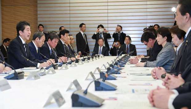 Japan's Prime Minister Shinzo Abe (L) attends a meeting at the new COVID-19 coronavirus infectious disease control headquarters at the prime minister's office in Tokyo