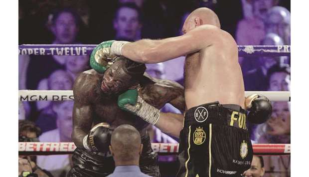 British boxer Tyson Fury (R) lands a punch on US boxer Deontay Wilder during their World Boxing Council (WBC) Heavyweight Championship title bout at the MGM Grand Garden Arena in Las Vegas on Saturday. At bottom, Fury celebrates after his win.