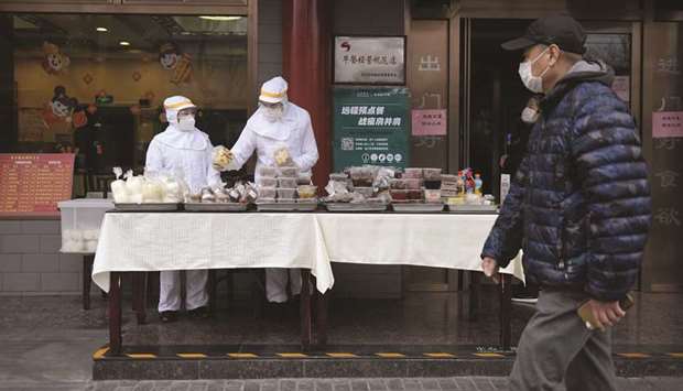 Restaurant workers wearing protective clothing as a preventive measure against the coronavirus as they prepare food to sell on the street outside their restaurant in Beijing.