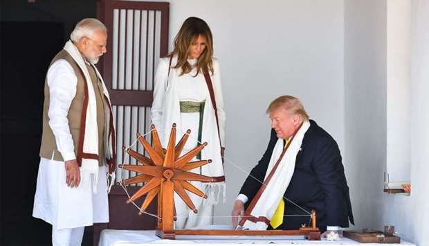 US President Donald Trump (R) and First Lady Melania Trump (C) are accompanied by India's Prime Minister Narendra Modi as they visit the Gandhi Ashram in Ahmedabad