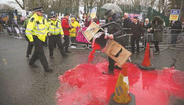 A woman spills red paint from a trolley as police officers approach, as demonstrators gather in support of WikiLeaks founder Julian Assange, outside Woolwich Crown Court yesterday.