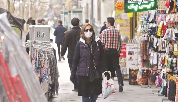 A woman wears a protective mask while walking along the side of a street in the Iranian capital Tehran, yesterday.