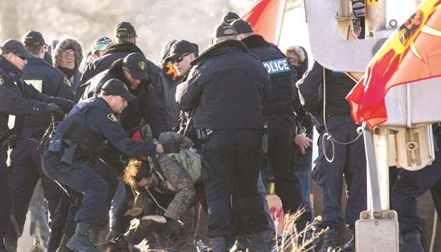 Police officers make an arrest during a raid on a Tyendinaga Mohawk Territory camp next to a railway crossing in Tyendinaga, Ontario.